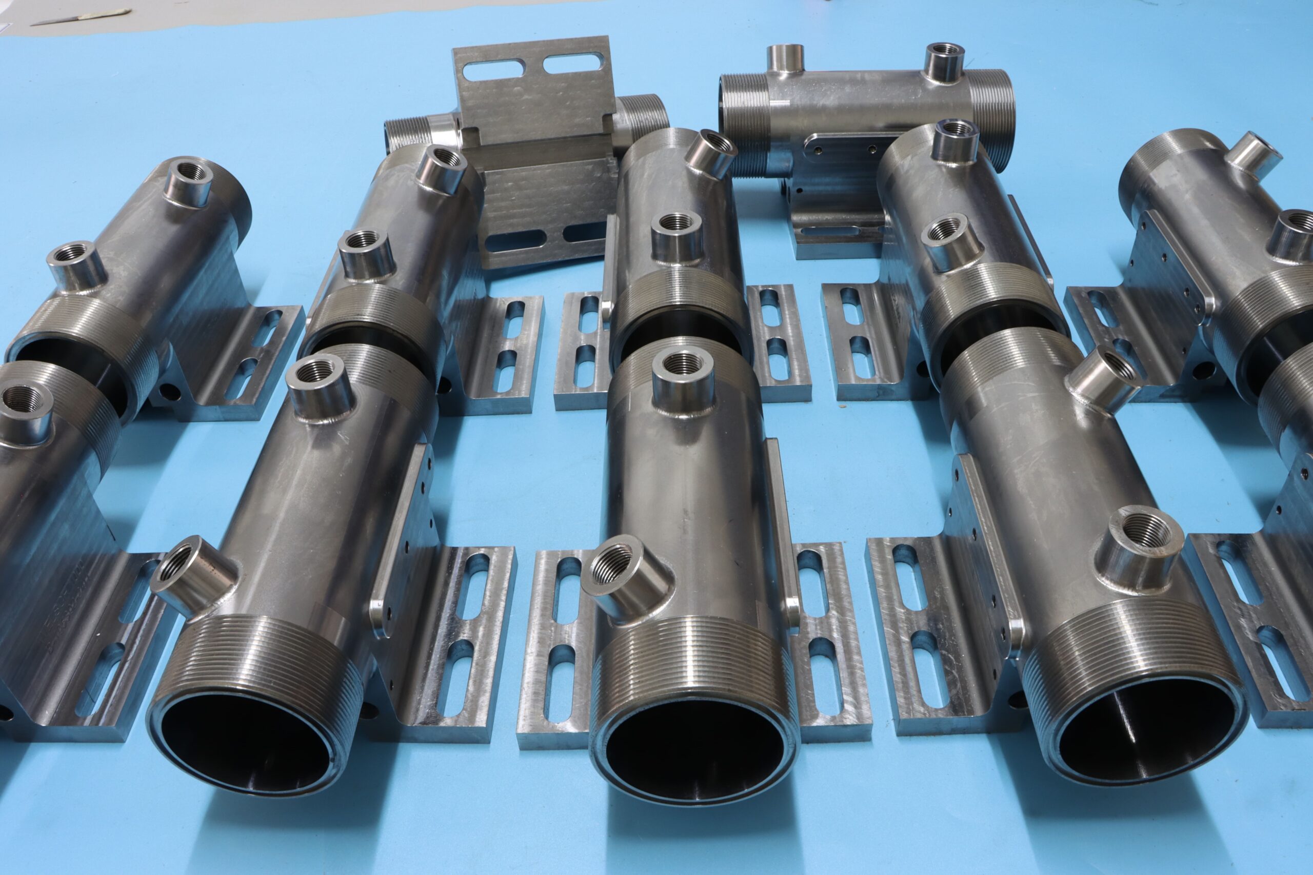 Heavy-duty welded industrial manifold cylinders and custom hydraulic steel piping with threaded ports.